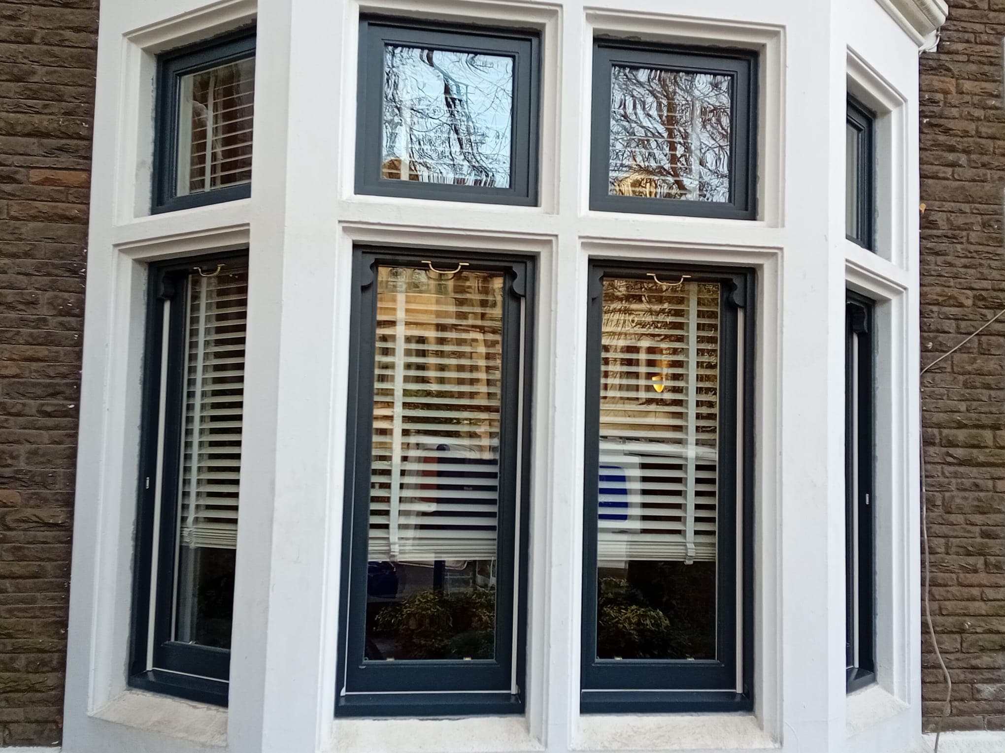 Large-scale Victorian sash window restoration with dark green painted timber frames